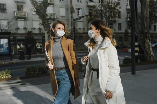 Free Two women wearing face masks walking outdoors, showcasing pandemic lifestyle. Stock Photo