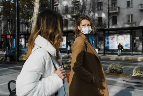 Free Two women wearing face masks walk on a city street, embracing new normal practices. Stock Photo