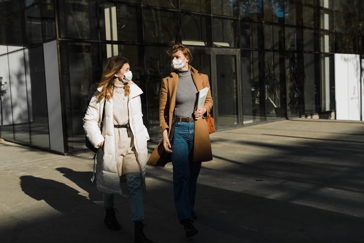 Women Wearing Face Masks Walking Outside A Building