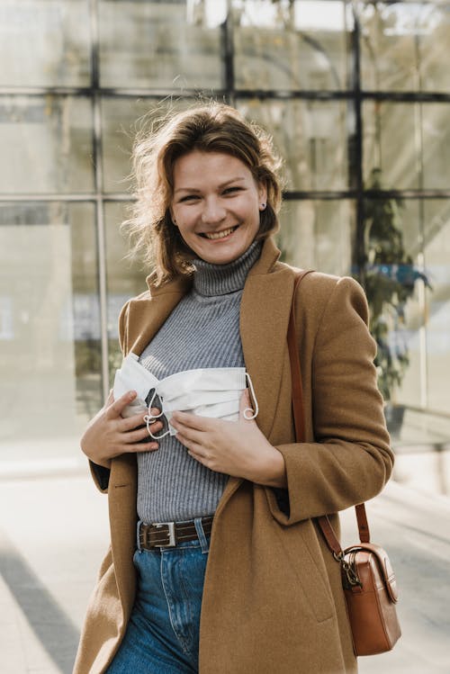 Wanita Dengan Mantel Coklat Dan Jeans Denim Biru Tersenyum