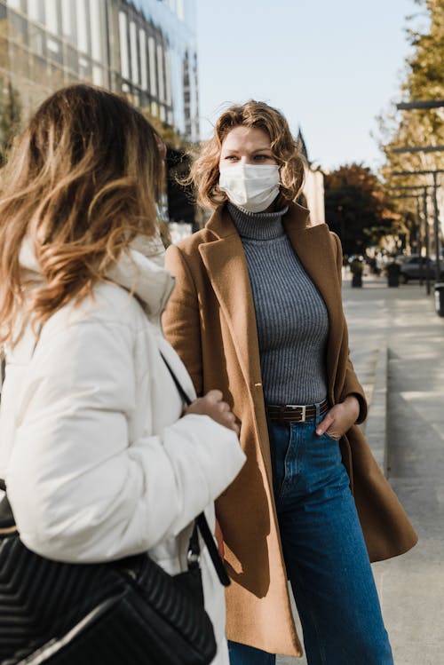 Femme En Manteau Blanc Et Jean Bleu Portant Un Masque Blanc