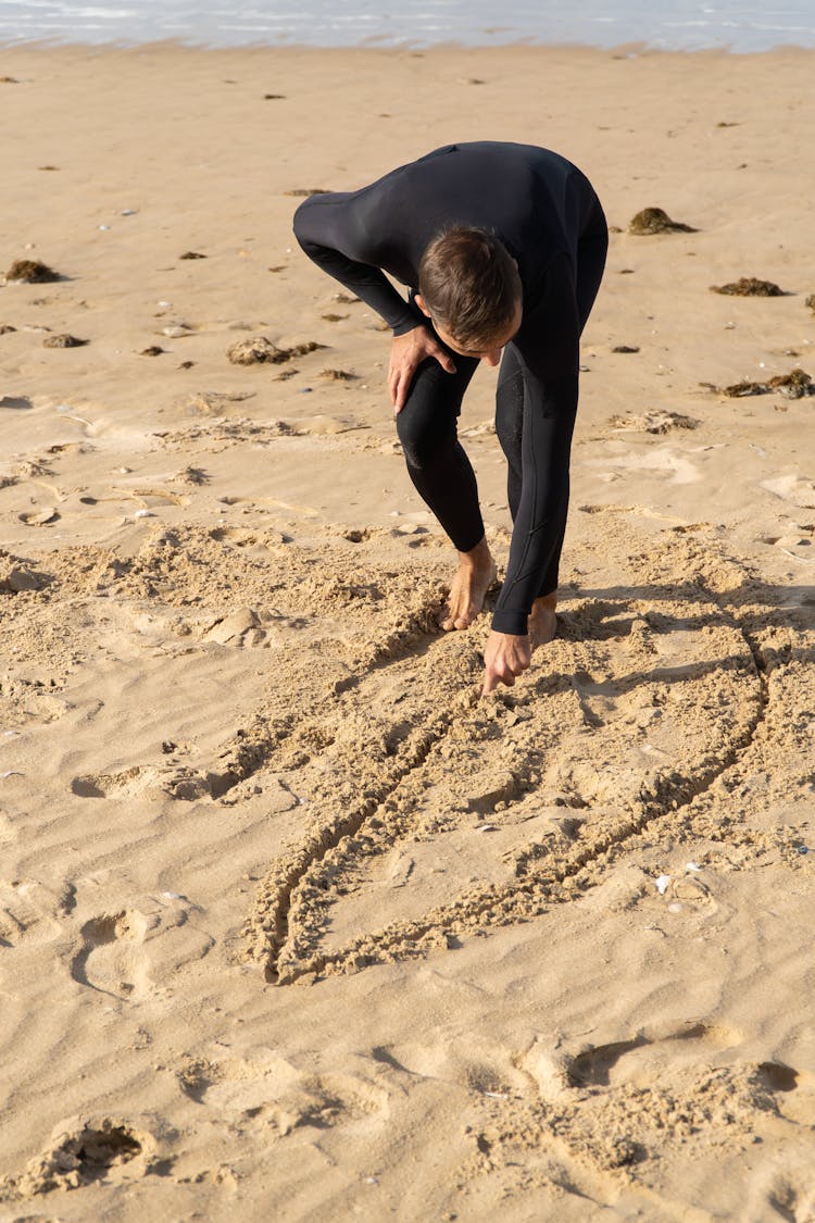 A Man Drawing On The Sand 