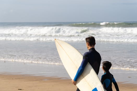 Father and son ready to surf on a Portuguese beach. Perfect day for waves.