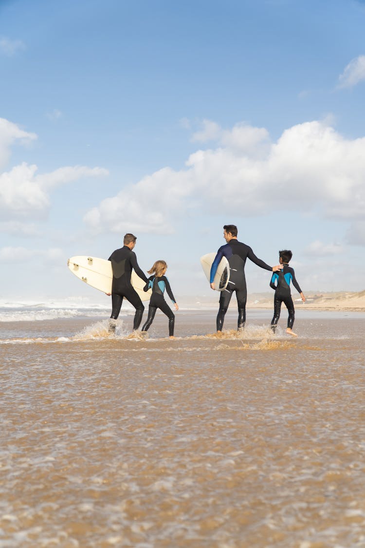 People Wearing Rash Guard Walking At The Beach