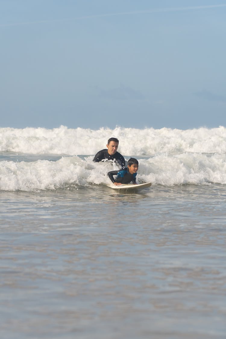 Boy Learning To Surf On Sea Waves