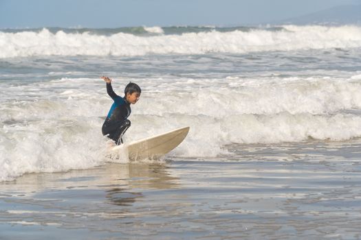 Boy surfing at a Portuguese beach, showcasing balance and skill on the waves.