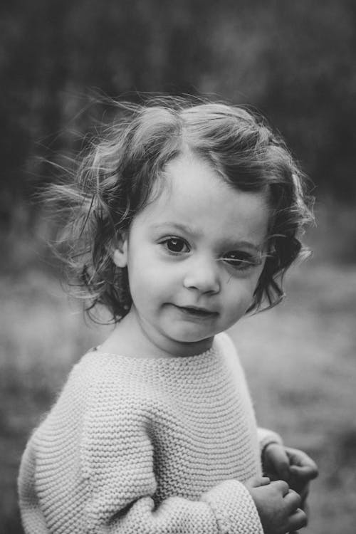 A Grayscale of a Girl Wearing a Knitted Sweater