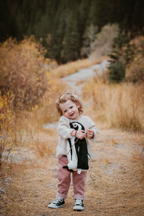 Free Portrait of a Cute Little Girl Holding Her Stuffed Toy Penguin Outdoors  Stock Photo