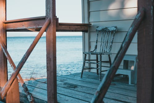 Old chair placed on wooden terrace of typical beach house with picturesque sea view on sunny day