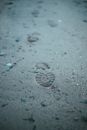 Sandy road with stones and footprints