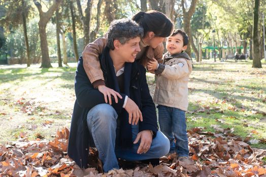 A family enjoying a sunny autumn day in a leafy park.