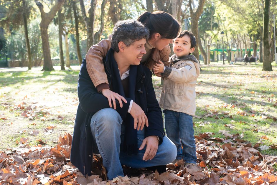Una familia disfrutando de un soleado día de otoño en un parque lleno de hojas.