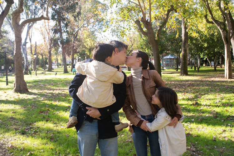 A Couple Kissing While With Their Kids