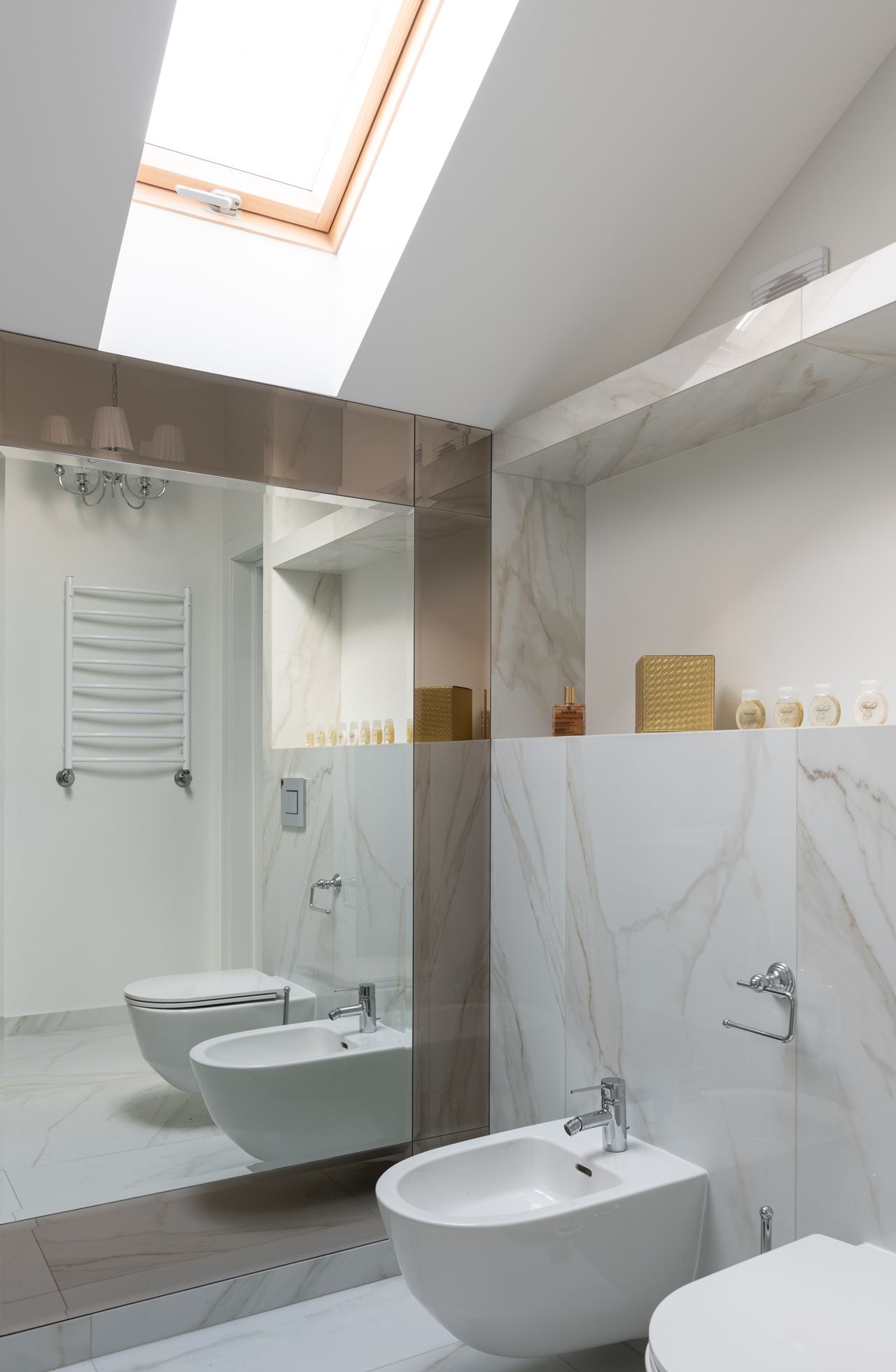 Wall-hung toilet reflected in mirror beside a bidet