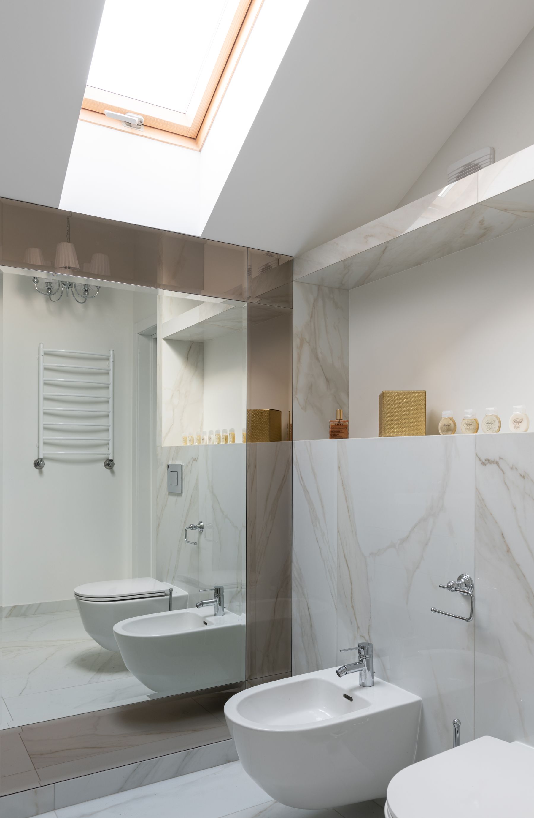 Contemporary bathroom with a toilet and adjacent bidet arranged against a tiled wall