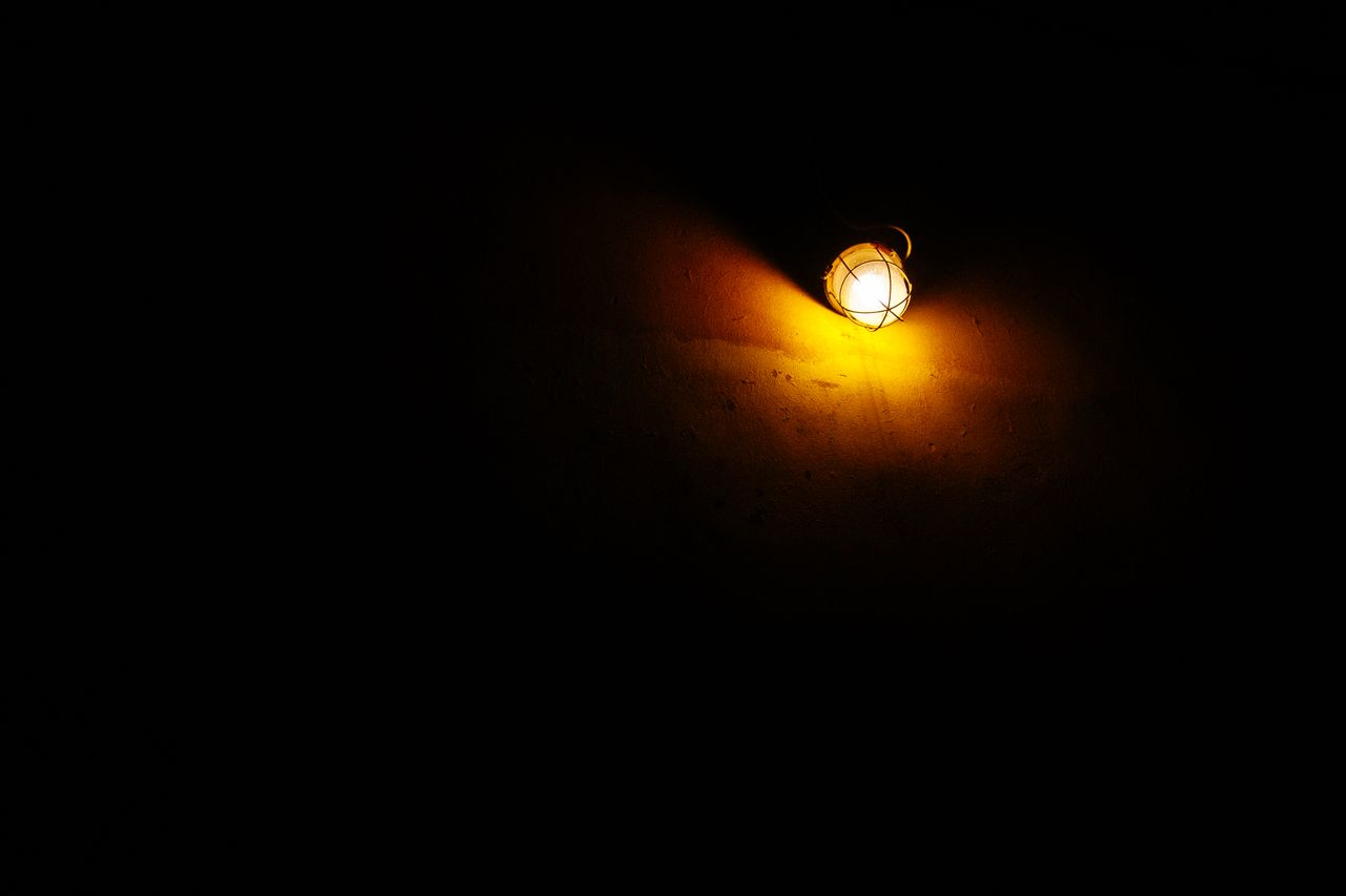 a single wall lamp casts a warm glow in a dark environment creating a
