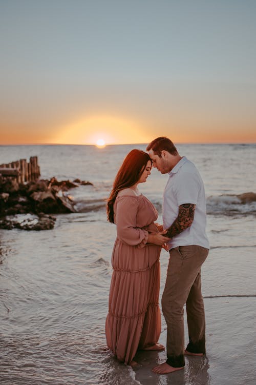 Free Loving pregnant couple standing together on sunset seacoast Stock Photo