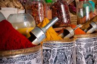 Metal containers with assorted aromatic spices and glass jars with dried herbs placed in row in local oriental market