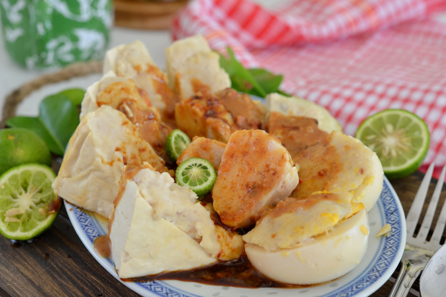 Traditional Indonesian tofu and siomay dish garnished with fresh lime, served with peanut sauce on a decorative platter.