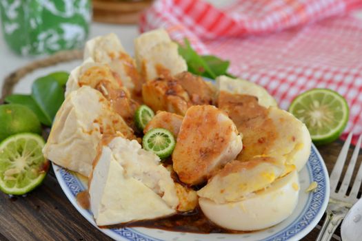 Traditional Indonesian tofu and siomay dish garnished with fresh lime, served with peanut sauce on a decorative platter.