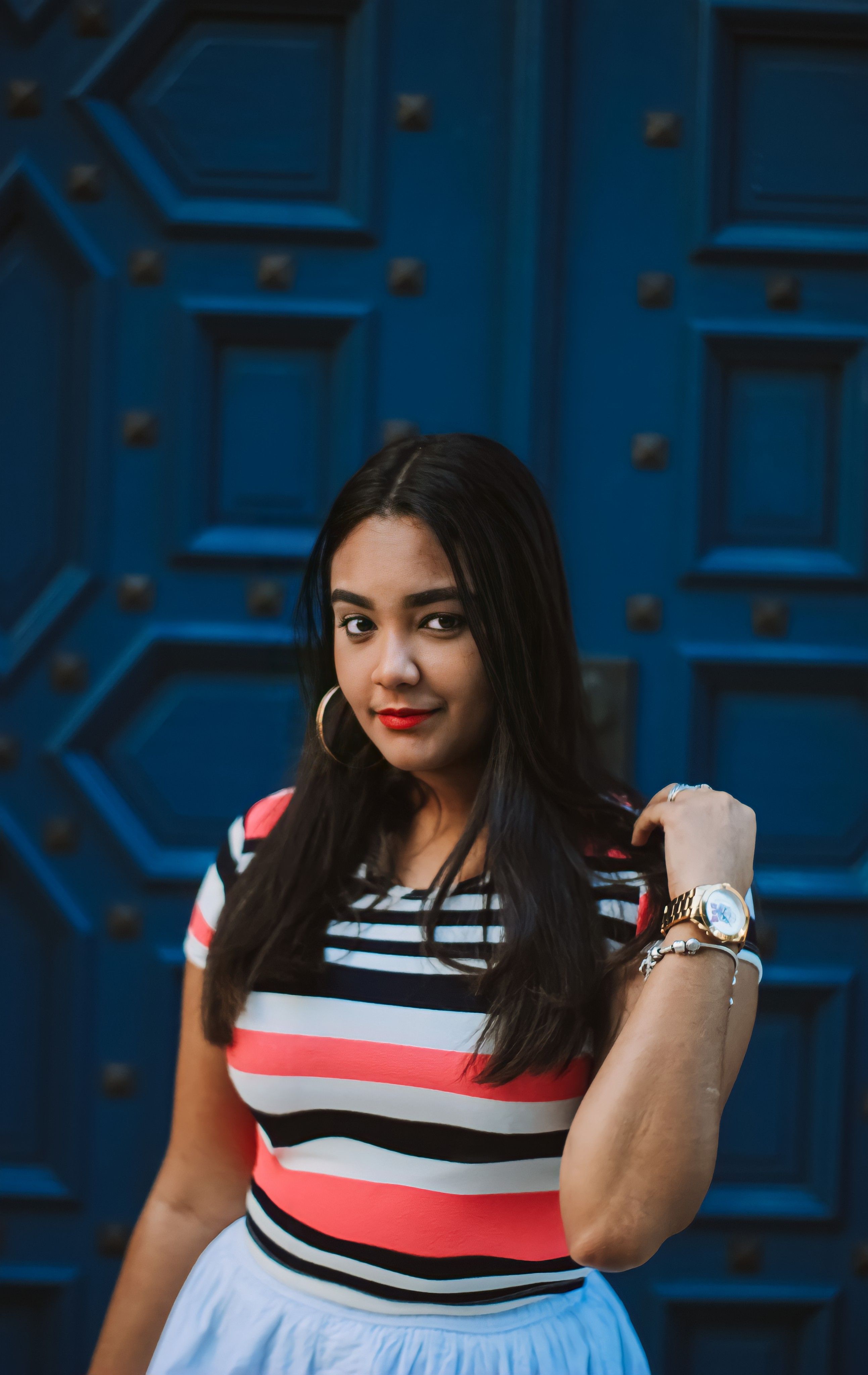 gratis Een Vrouw In Een Gestreept Shirt Staat Naast De Blauwe Achtergrond Stockfoto