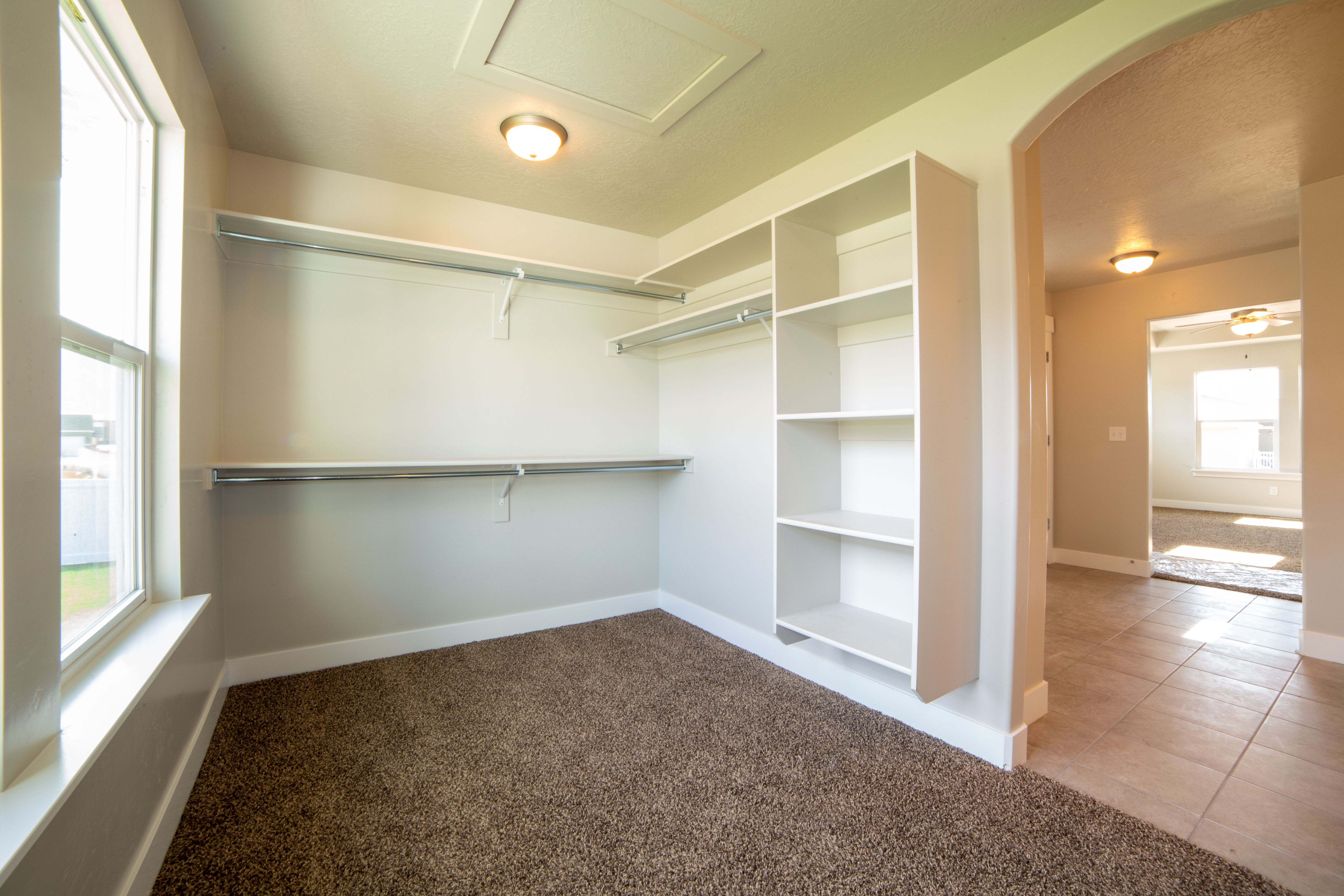 Bright and spacious modern closet with white walls and carpet flooring.