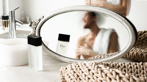 Reflection of unrecognizable young shirtless male in misted mirrors after taking shower in modern light bathroom