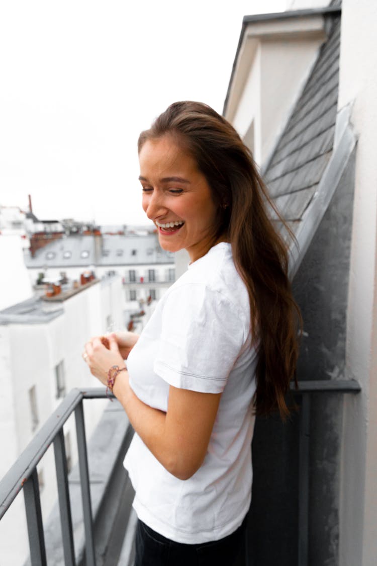 Young Cheerful Lady Standing On Balcony And Enjoying City View