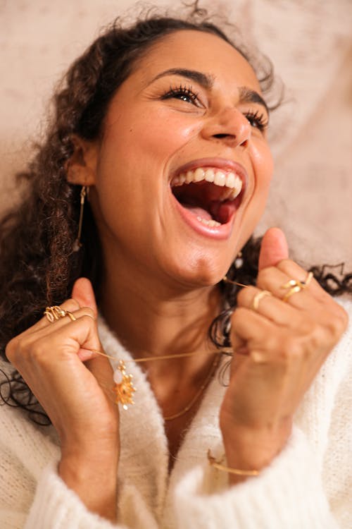 Free Cheerful young female with long curly hair in warm knitted sweater yelling happily and looking away Stock Photo