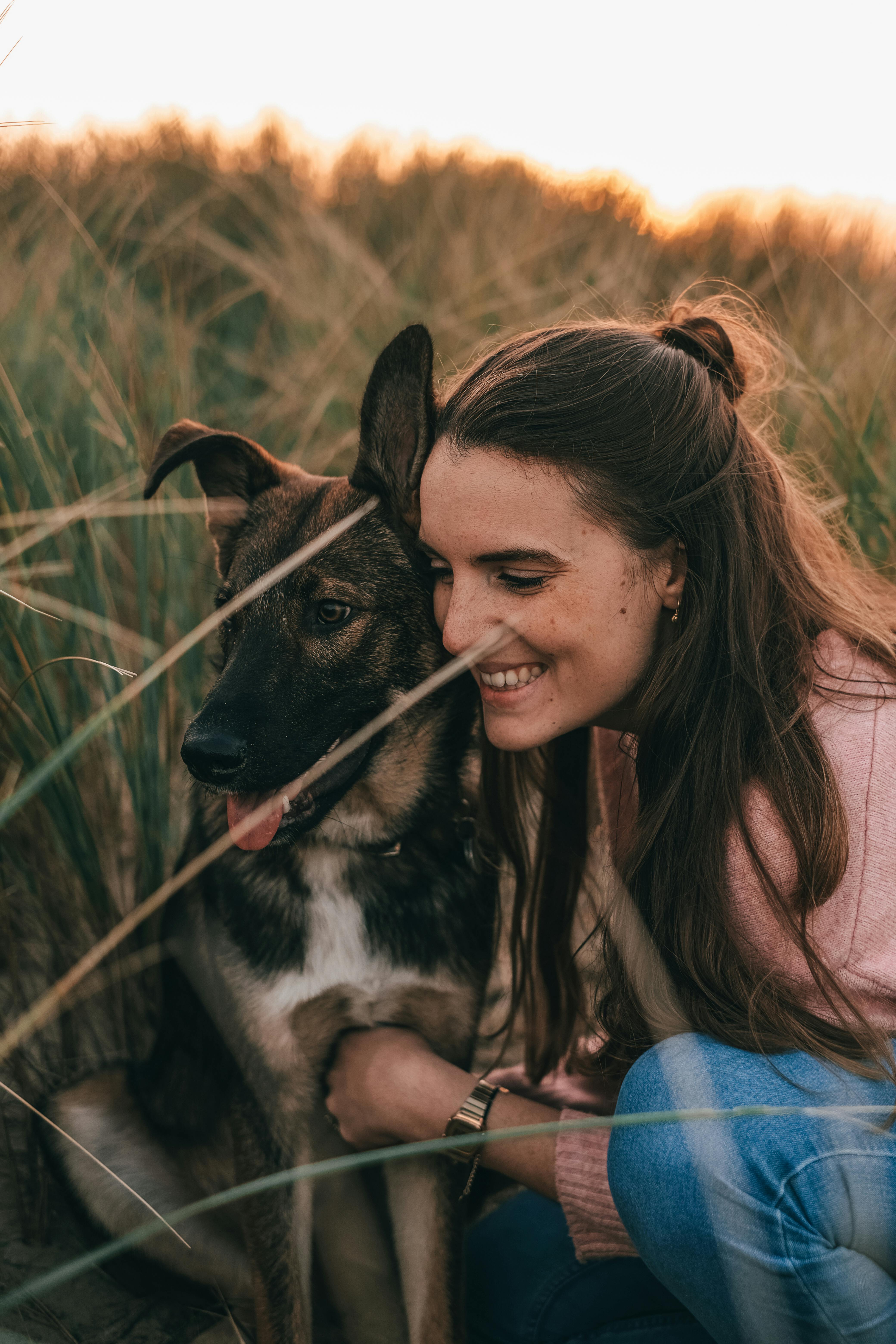 positive young woman embracing purebred dog in field