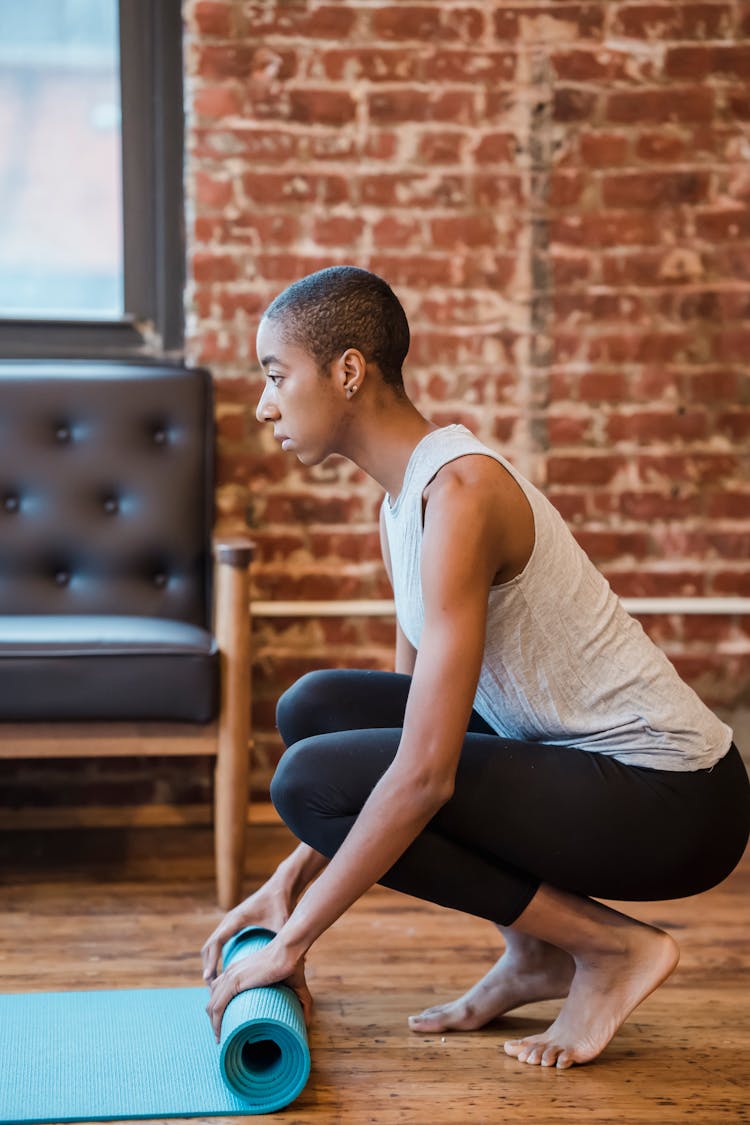 Black Female Opening Yoga Mat In Studio