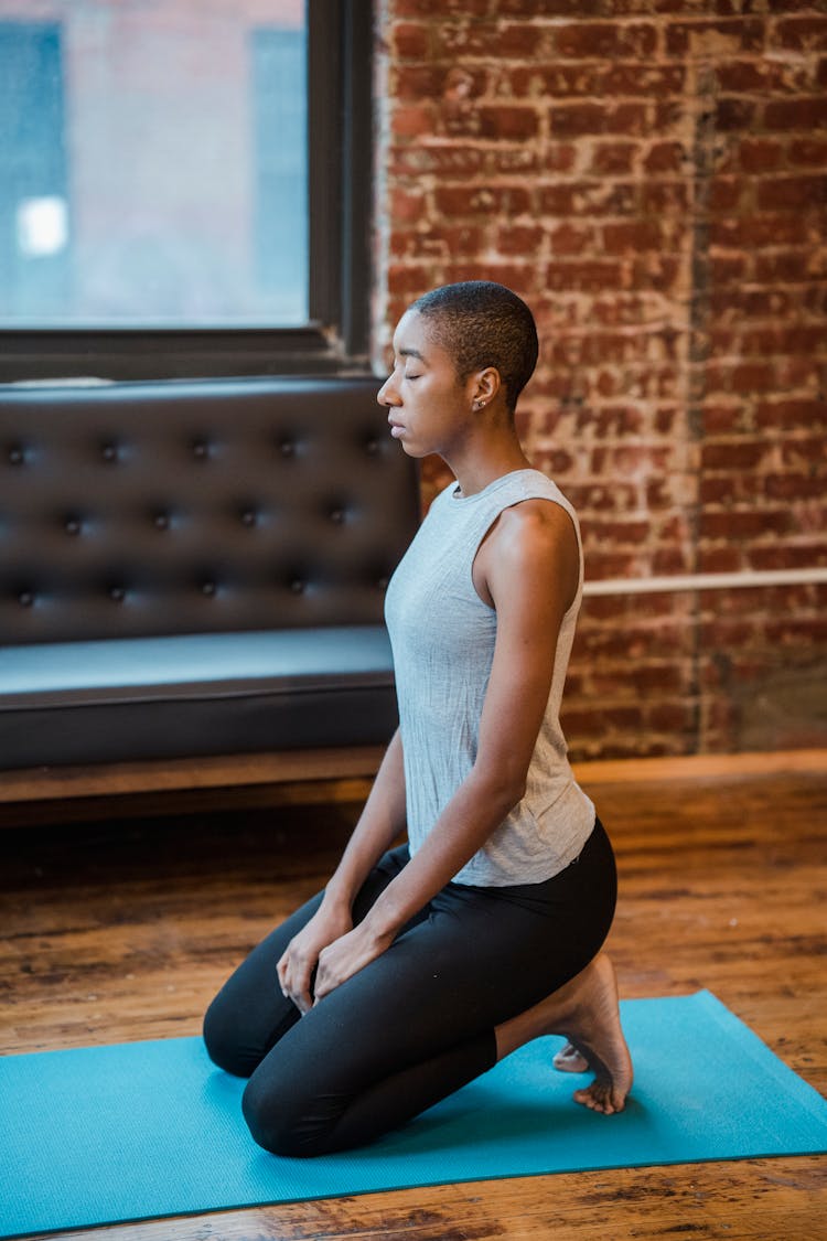 Black Female On Yoga Mat In Loft Near Couch