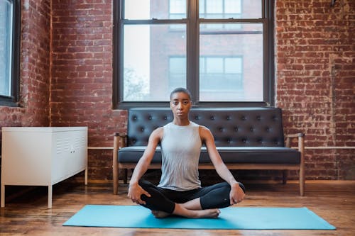 African American female meditating on yoga mat at home
