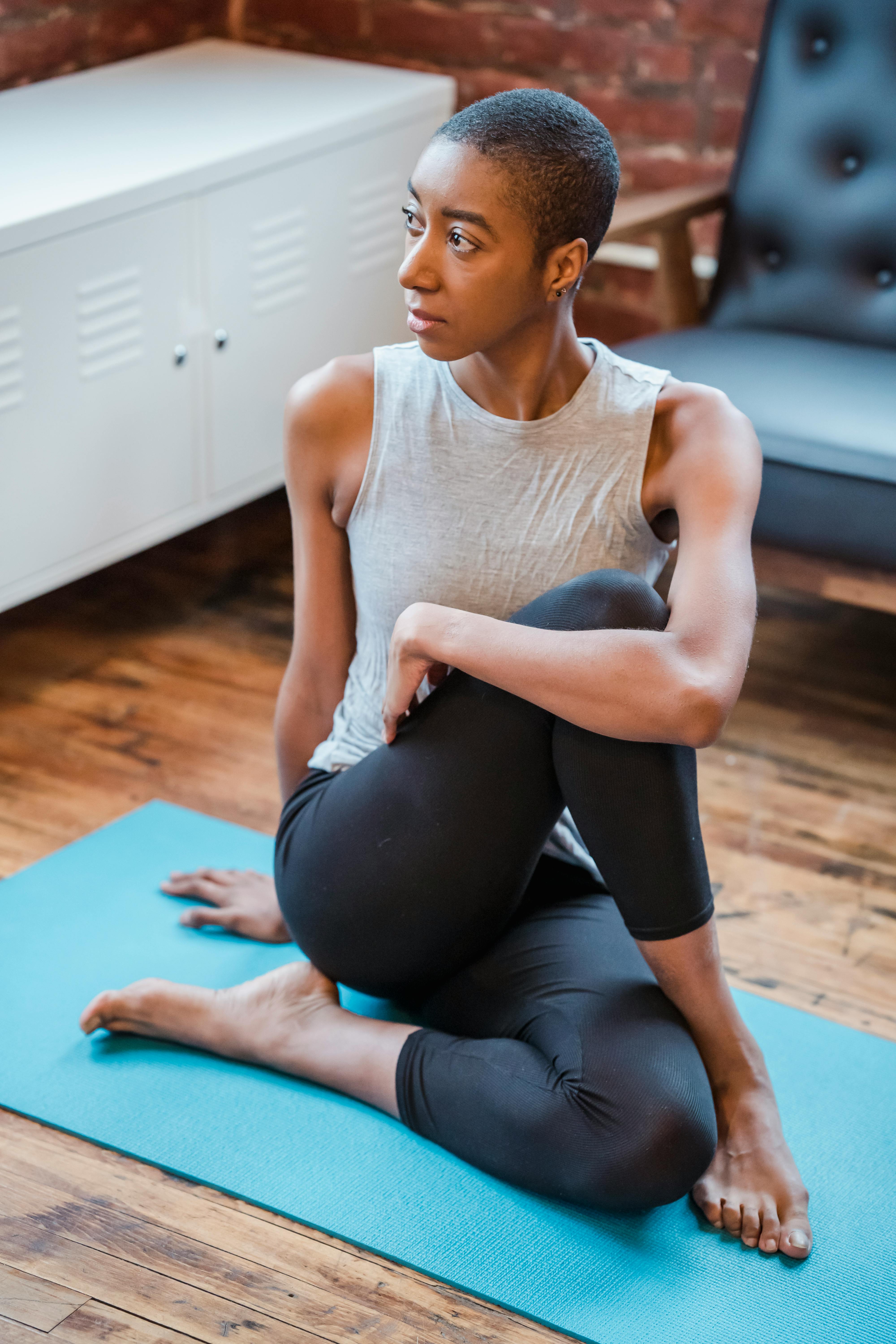 Serious black woman doing Ardha Matsyendrasana exercise · Free Stock Photo