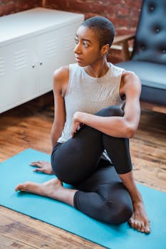 Active African American female exercising Half Lord of the Fishes asana while sitting on mat during yoga training on mat