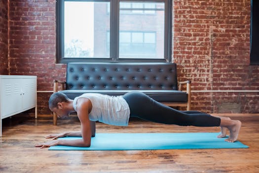 Focused African American woman performing a plank exercise on a yoga mat indoors.