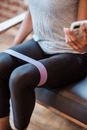 Crop sportswoman browsing smartphone while training with resistance band
