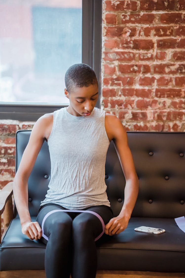 Black Woman With Elastic Band Looking At Smartphone During Workout