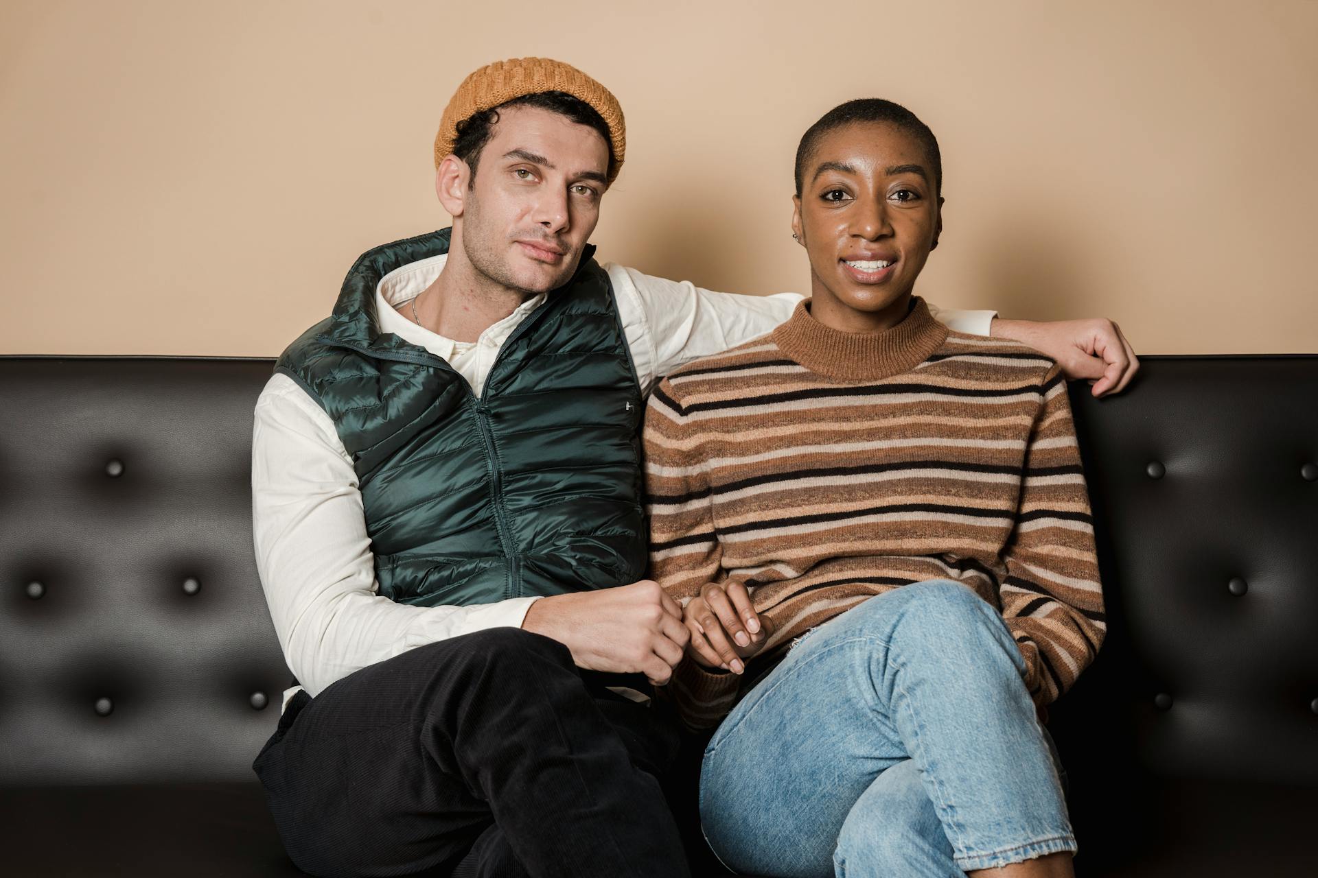 Content African American girlfriend with boyfriend looking at camera while sitting on comfortable sofa while spending time together in room