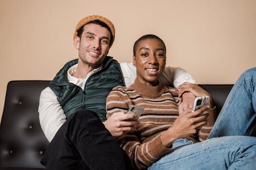 Free Cheerful multiethnic couple with smartphones Stock Photo