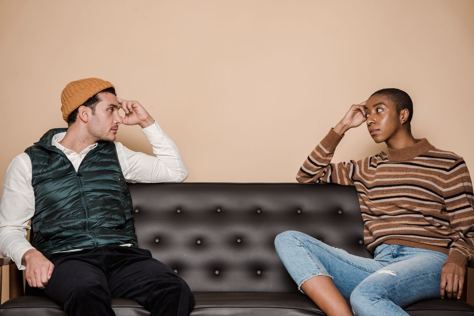 A couple sitting apart on a couch in a serious conversation, reflecting political differences in a relationship