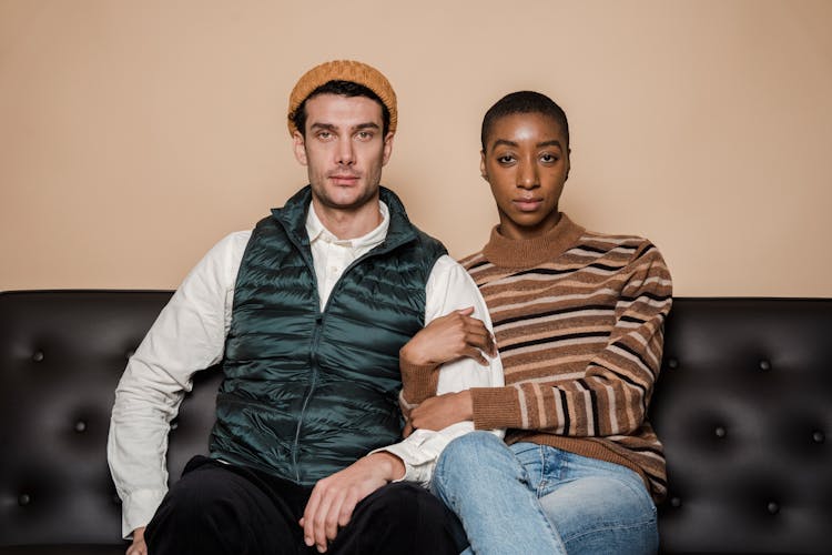 Serious Multiethnic Couple Sitting Close On Sofa