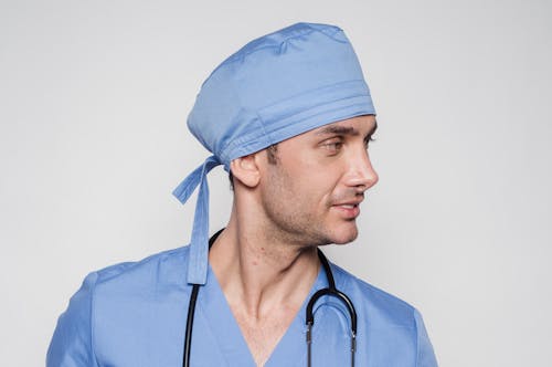 Free Medical practitioner with stethoscope in uniform smiling while looking away against white background Stock Photo