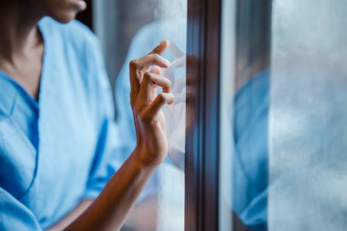 Black woman touching window while healing in hospital