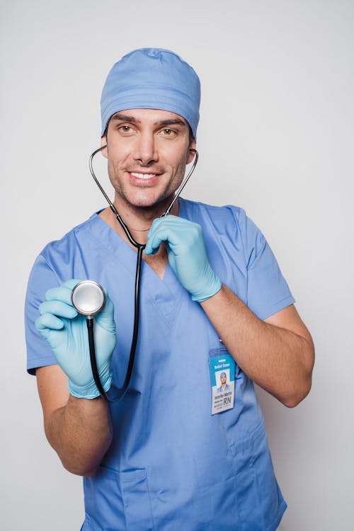 Positive doctor with stethoscope standing in light room