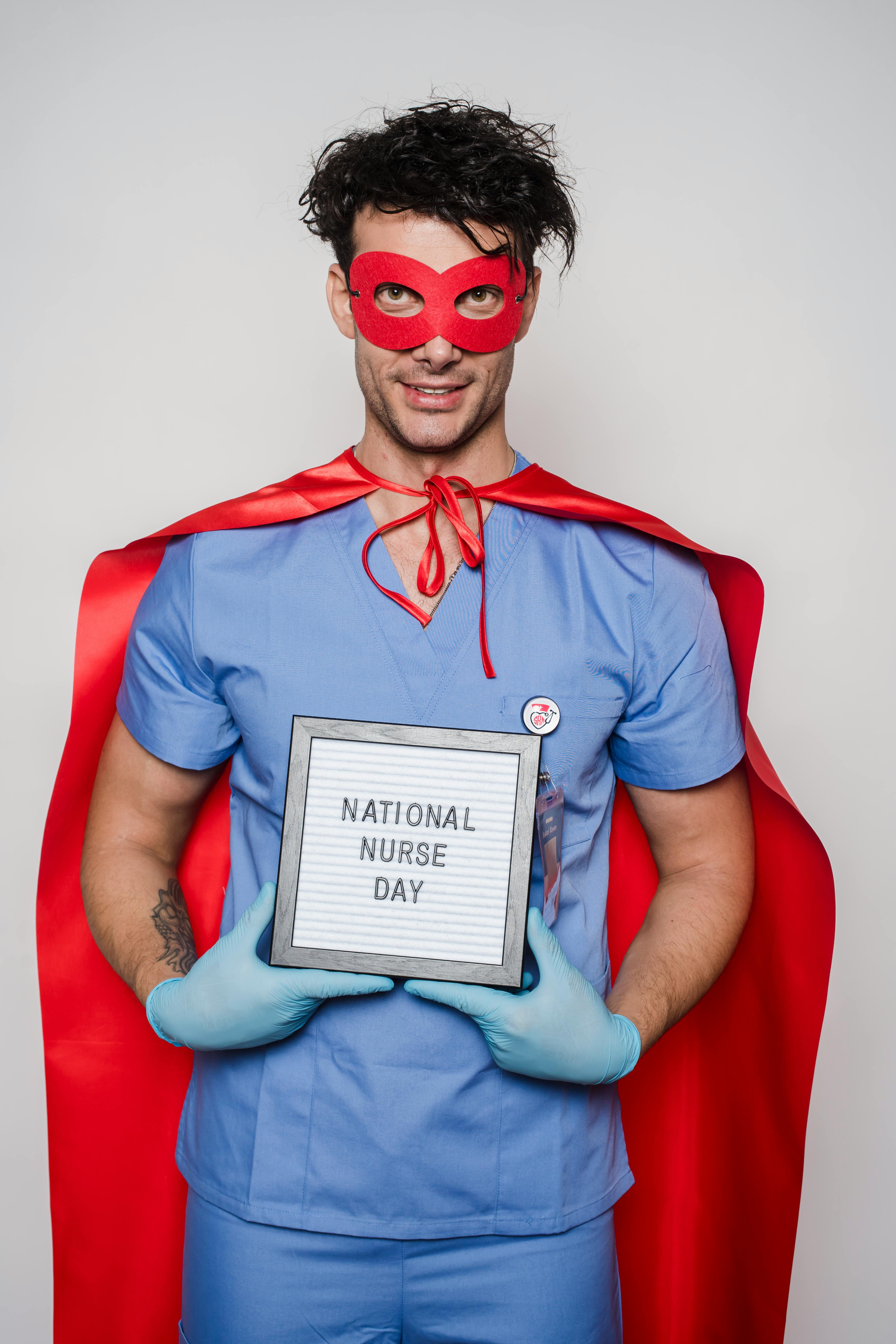 doctor in superhero costume showing card with national nurse day inscription