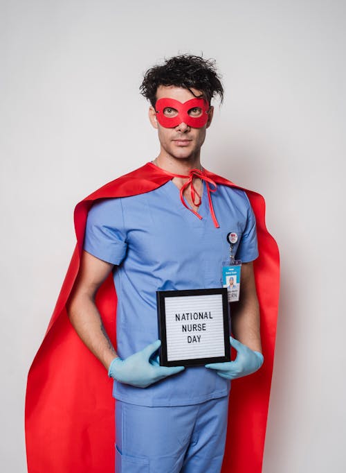 Serious doctor in superhero costume holding letterboard with National nurse day inscription