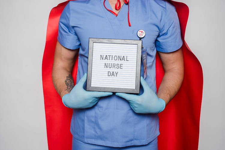 Doctor In Red Cape Showing Letterboard With National Nurse Day Inscription