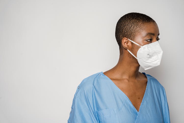 Black Woman Patient In Mask Looking Away In Light Room