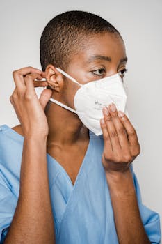 African American woman adjusts her mask for optimal protection.